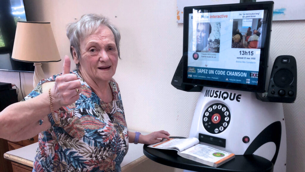 une femme leve le pouce devant la borne interactive melo