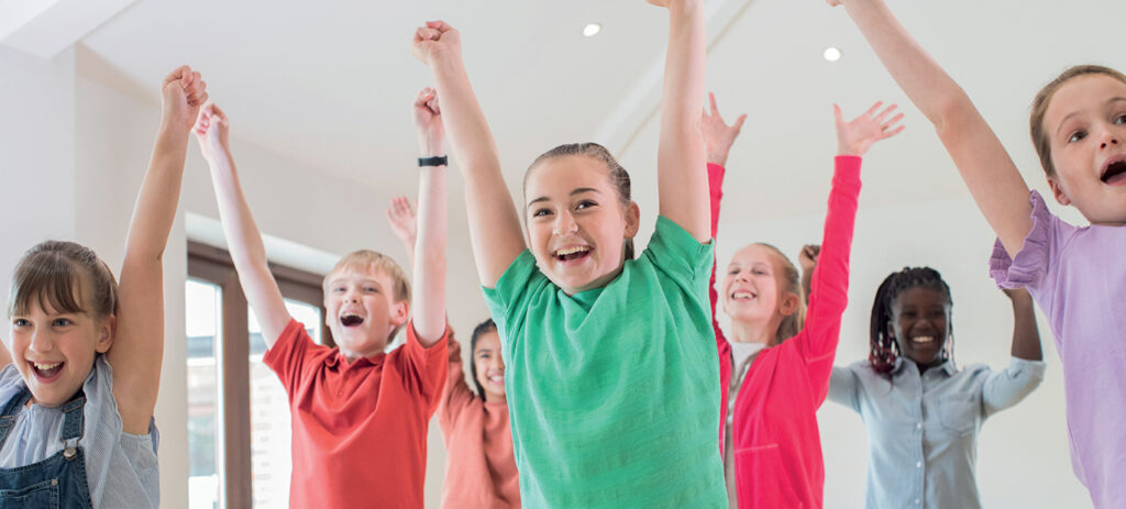 des enfants levent les bras en souriant