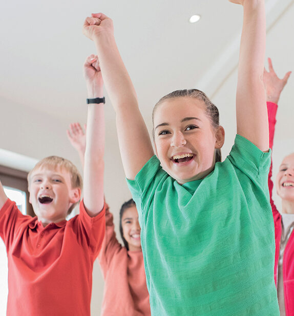 des enfants levent les bras en souriant