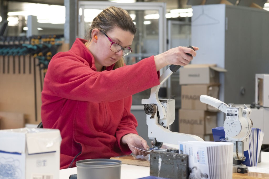 une femme perce des cartes avec une machine
