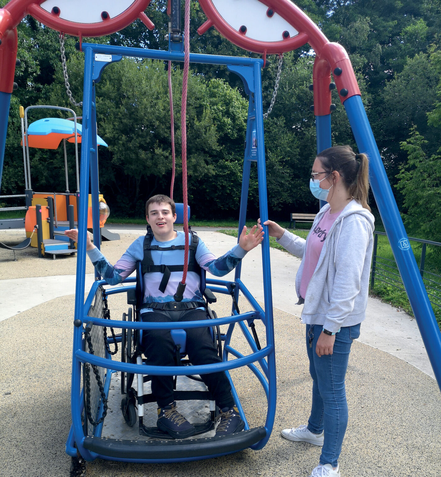 un jeune en fauteuil roulant fait de la balançoire