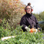 une femme taille la haie