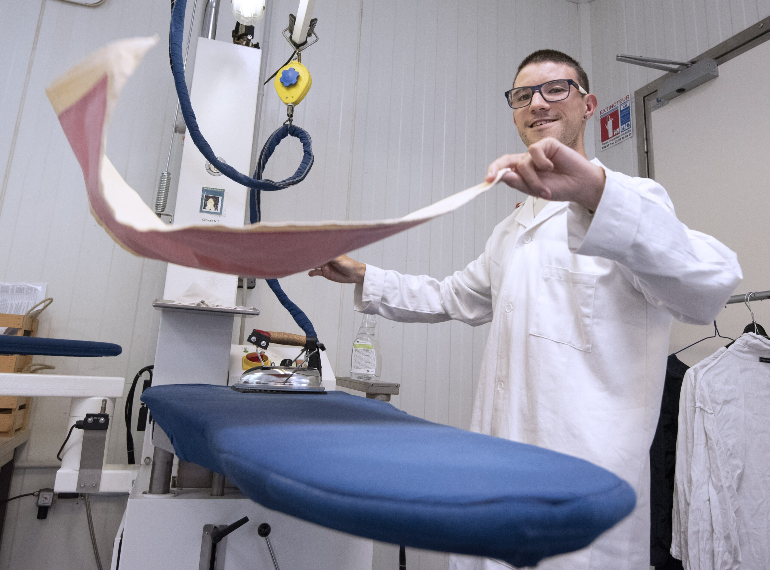 un homme repasse une serviette a l'atelier blanchisserie