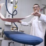 un homme repasse une serviette a l'atelier blanchisserie